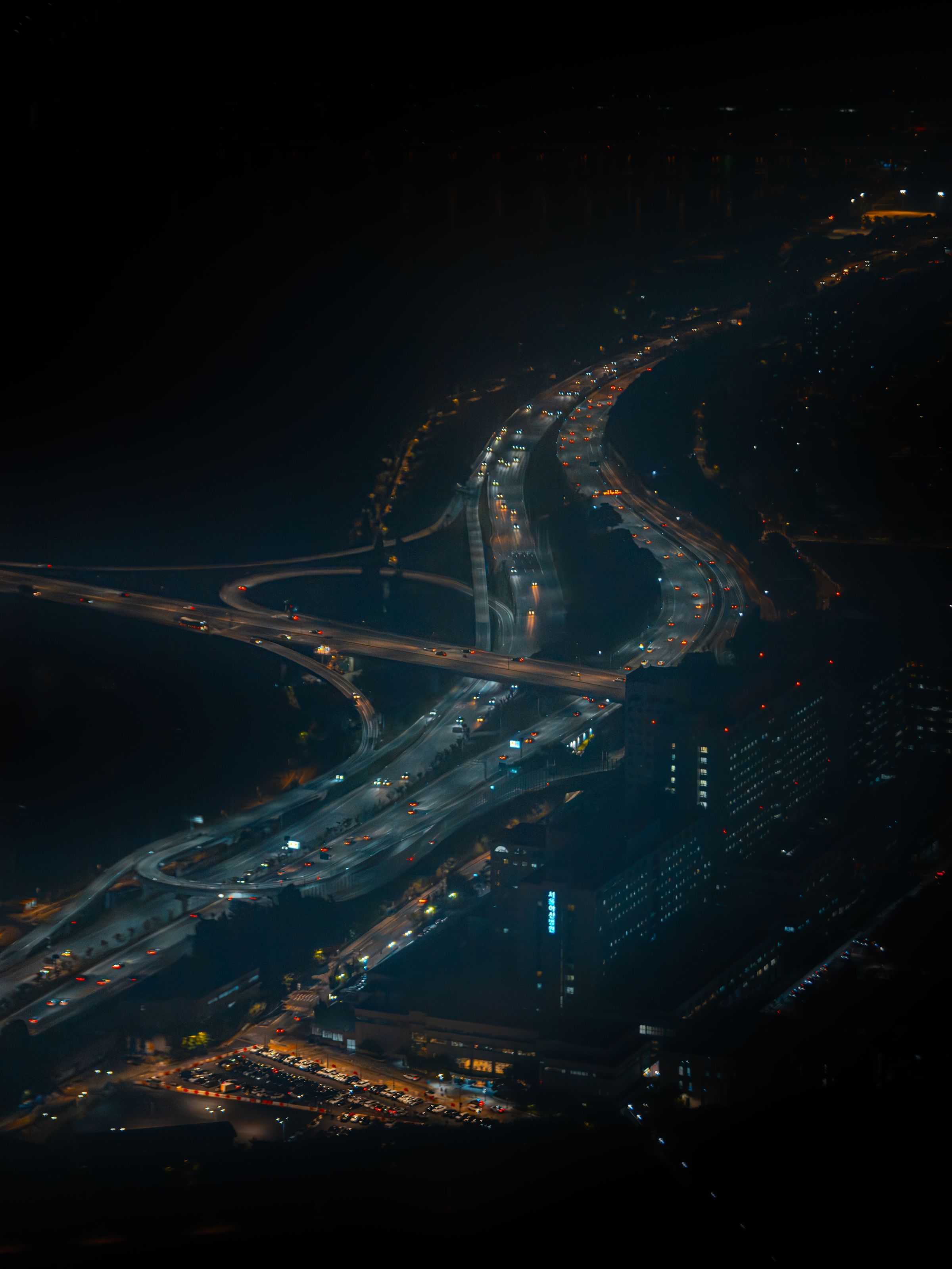 Aerial view of a highway interchange at night, lit by traffic